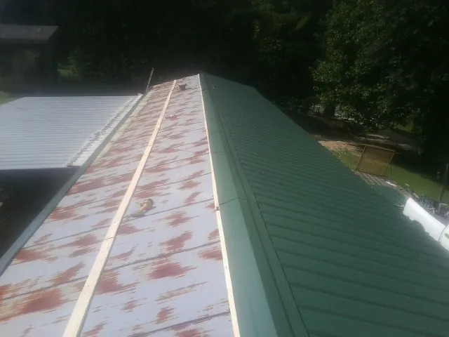Old rusted panels beside newly installed green metal roofing — Wind Damage Roof Repair by Roofing Brothers in Ghent