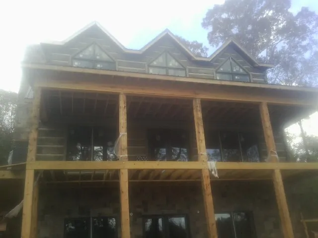 Dormers and porch framing on a large log home under construction — Roof Coating work by our crew in Ghent