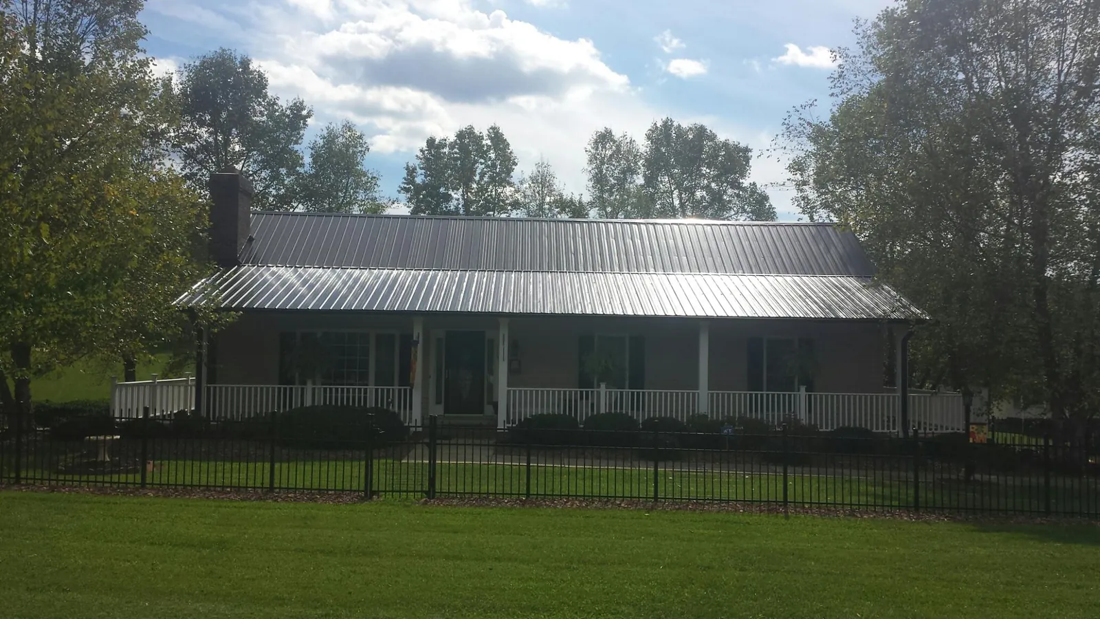 Gray metal roof on a brick ranch with a full width front porch — Gutter Guard Installation work by our crew in Ghent