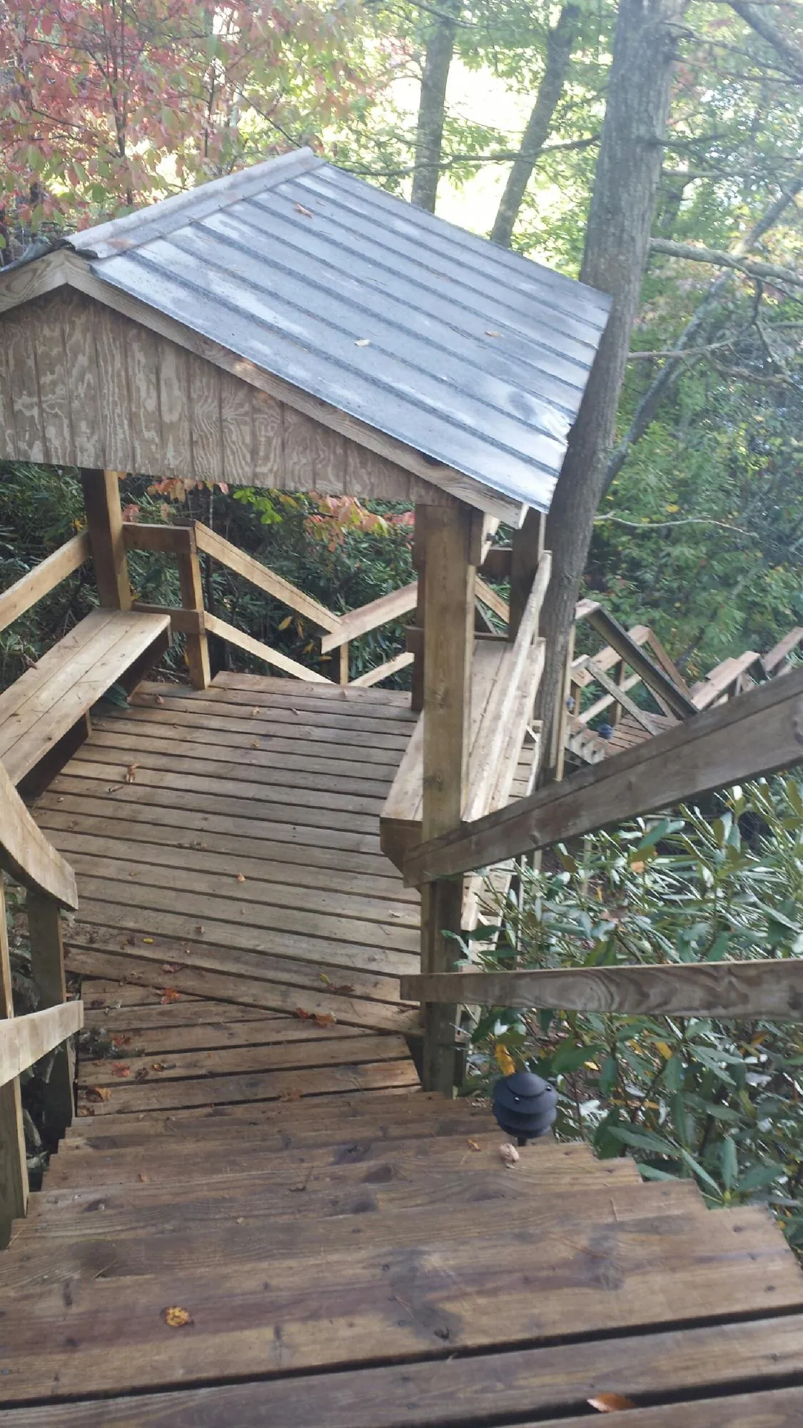 Metal roofed shelter over wooden steps on a wooded walkway — Skylight Repair & Installation work by our crew in Ghent