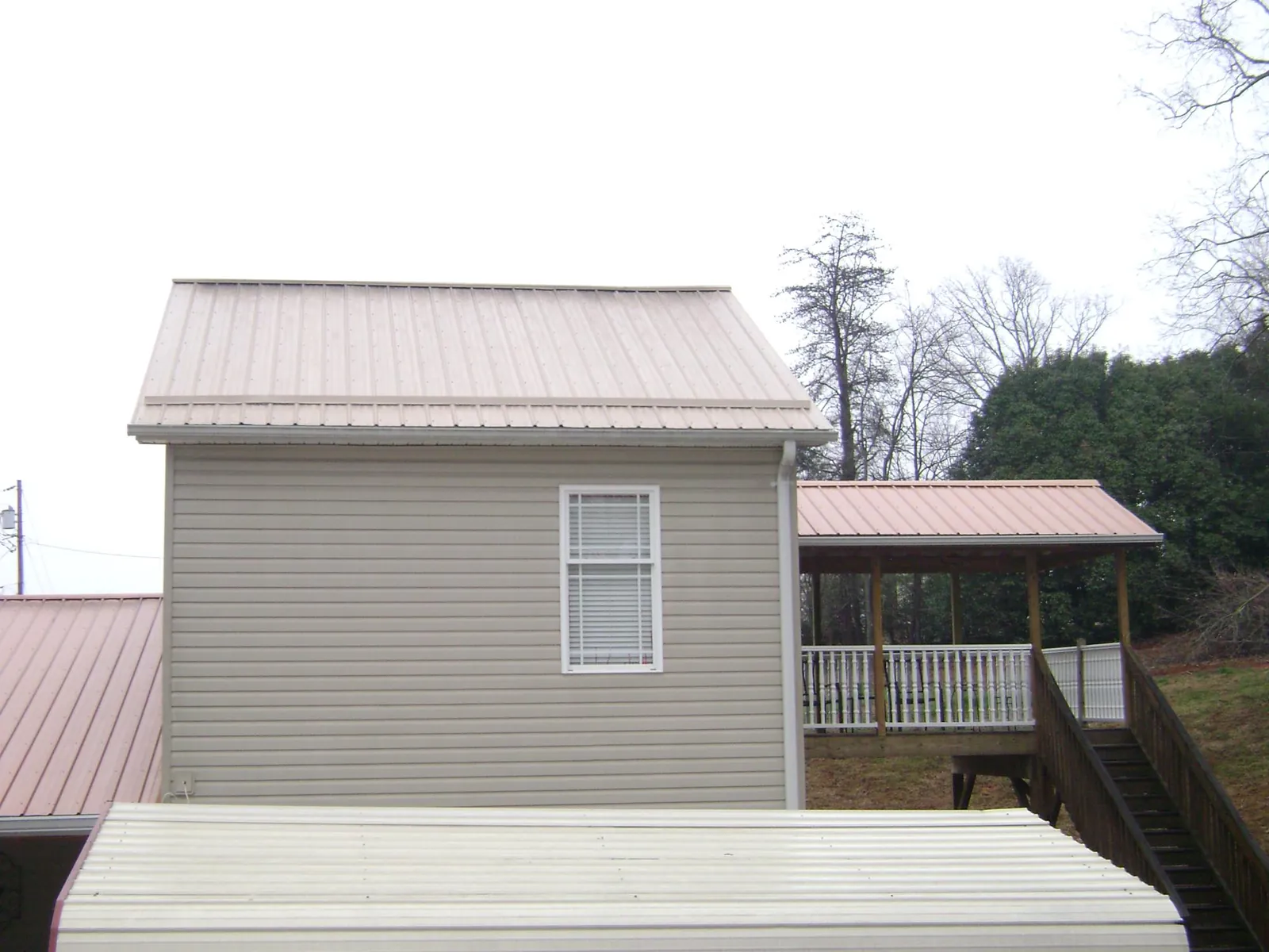 Tan metal roofs on a two story addition and attached porch, from a Roof Replacement job in Ghent