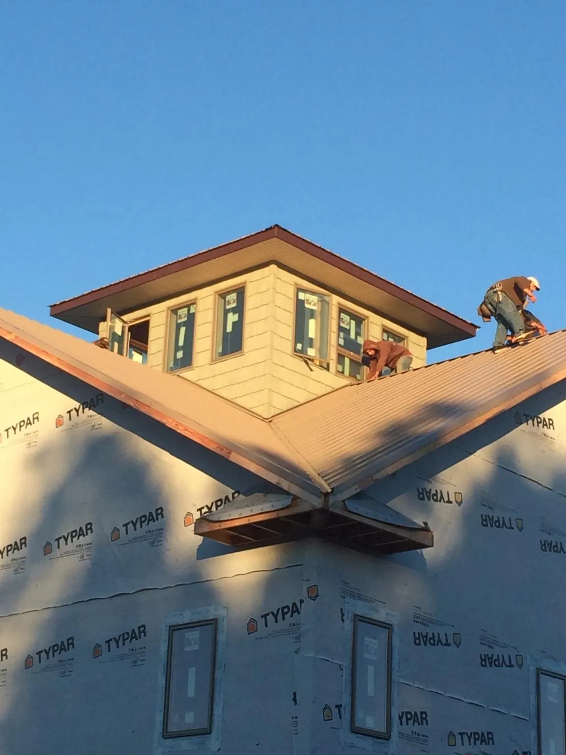 Roofers working around a rooftop cupola on a new metal roof at sunset — Roof Waterproofing in Ghent by Roofing Brothers